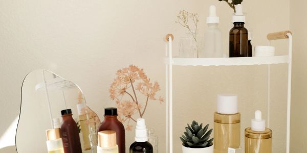 Skincare products and decor on a shelf with a small mirror.