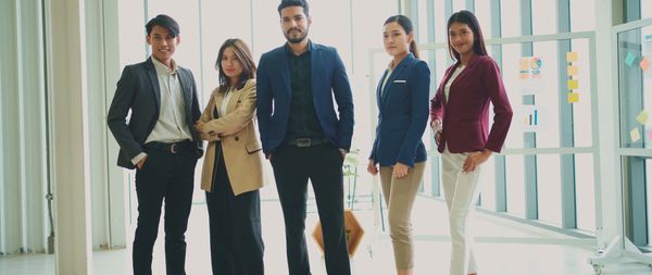 Confident young professionals posing together in a modern office setting.