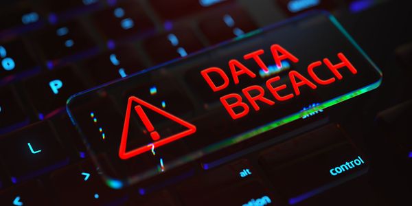 Magnifying glass on keyboard showing 'DATA BREACH' alert.