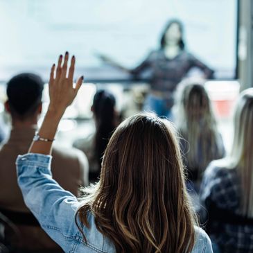 Student raising hand during a classroom lecture.