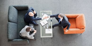 Tres personas en una reunión de negocios con apretón de manos.