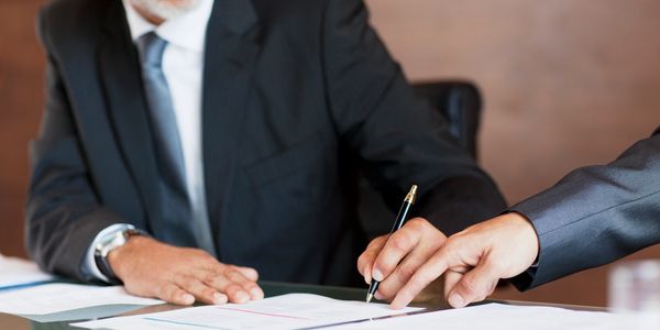 Hand unterschreibt ein Dokument mit Füller