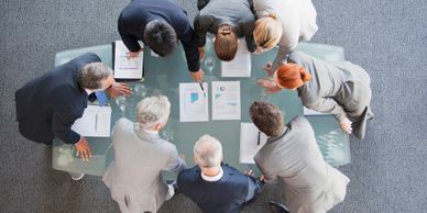 Business team reviewing documents around a glass table in a meeting.