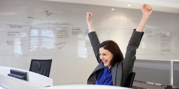 Excited businesswoman celebrating success at her desk.