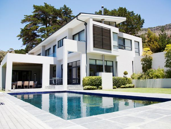 Modern white two-story house with a swimming pool and outdoor seating area.