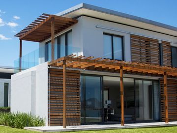 Modernes Haus mit Holzterrasse und großflächigen Fenstern.