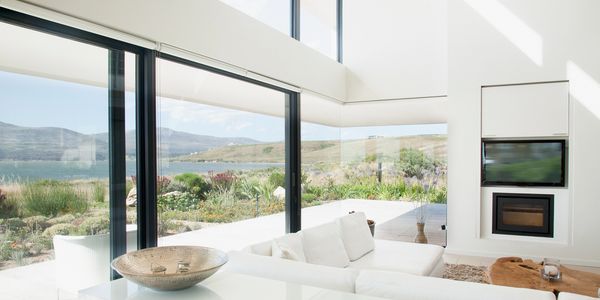 Bright modern living room with large windows overlooking a scenic lake and hills.