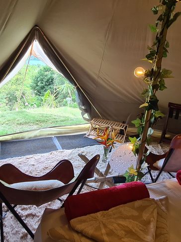 Cozy glamping tent interior with rustic chairs and a view of greenery.