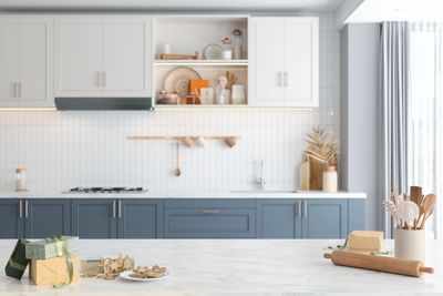 Modern kitchen with blue lower cabinets and white upper cabinets, decorated with kitchenware and gifts.
