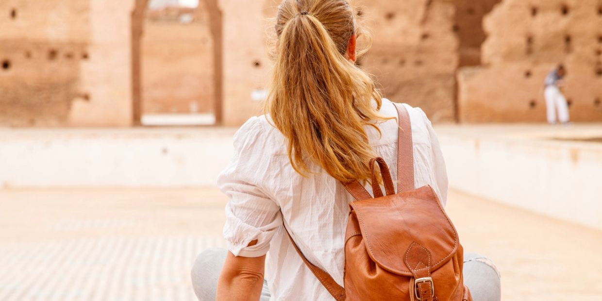Woman with ponytail and brown leather backpack in historical site.