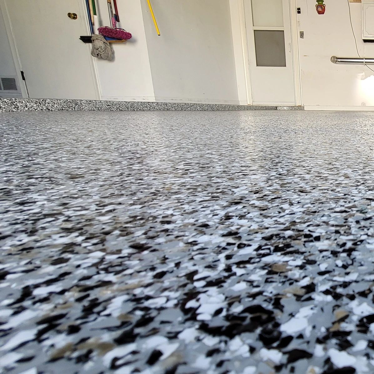 Flake epoxy garage floor with hanging tools and appliances in the background