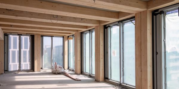 Room under construction with wooden beams and large windows.