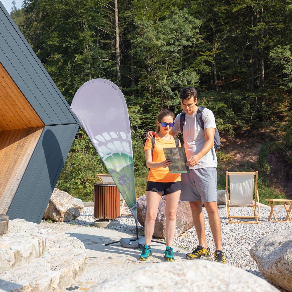 Couple hiking in the forest looking at a map near a modern cabin.