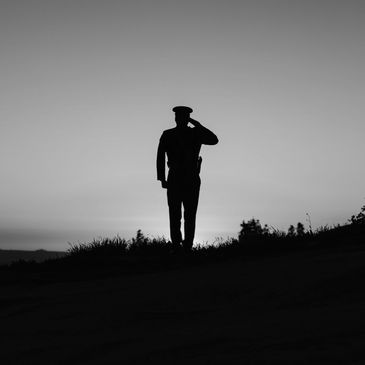 A military veteran saluting while looking out at the horizon.