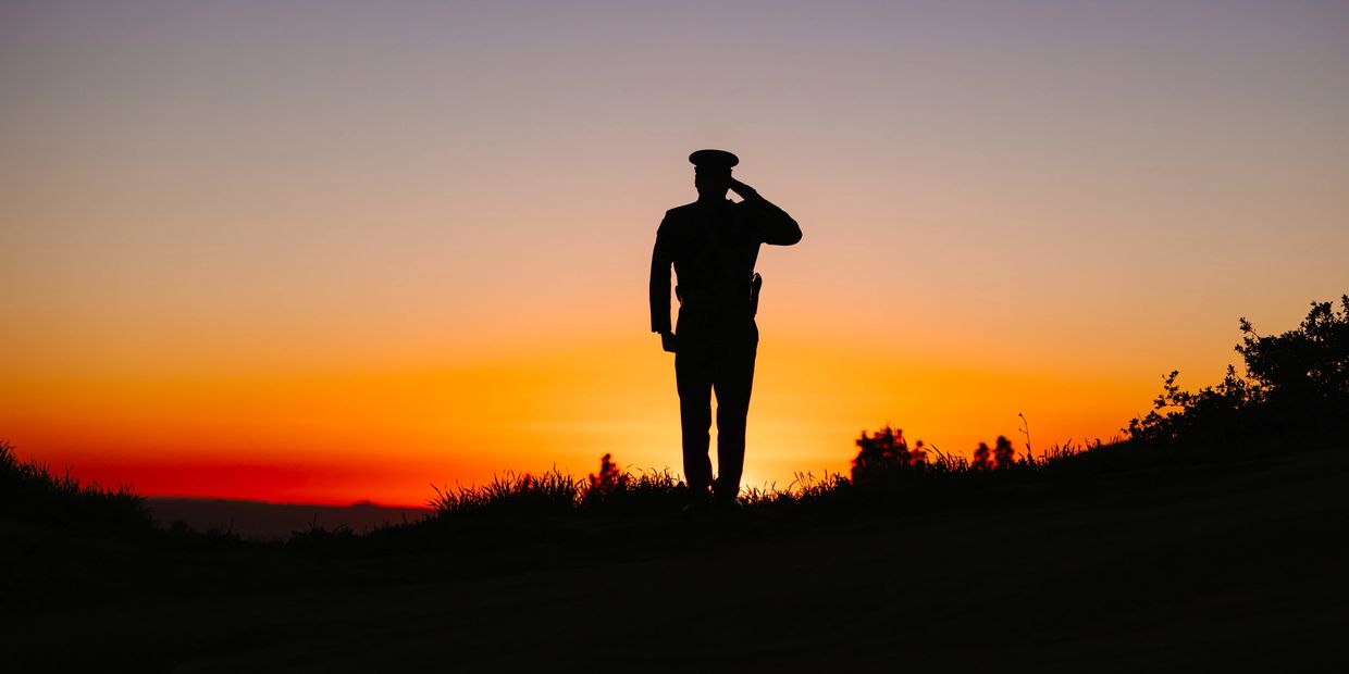 A soldier standing at attention as the sun sets.