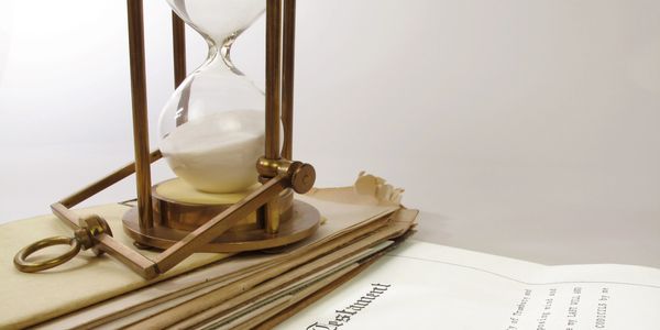 An hourglass resting on a stack of old newspapers with a white background.