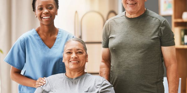 Caregiver smiling with elderly couple at home.