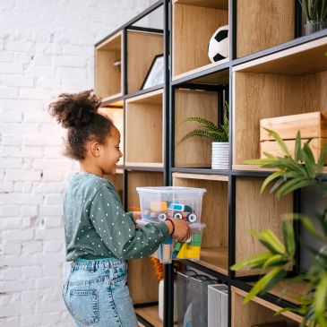 Child organizing toys on shelves.