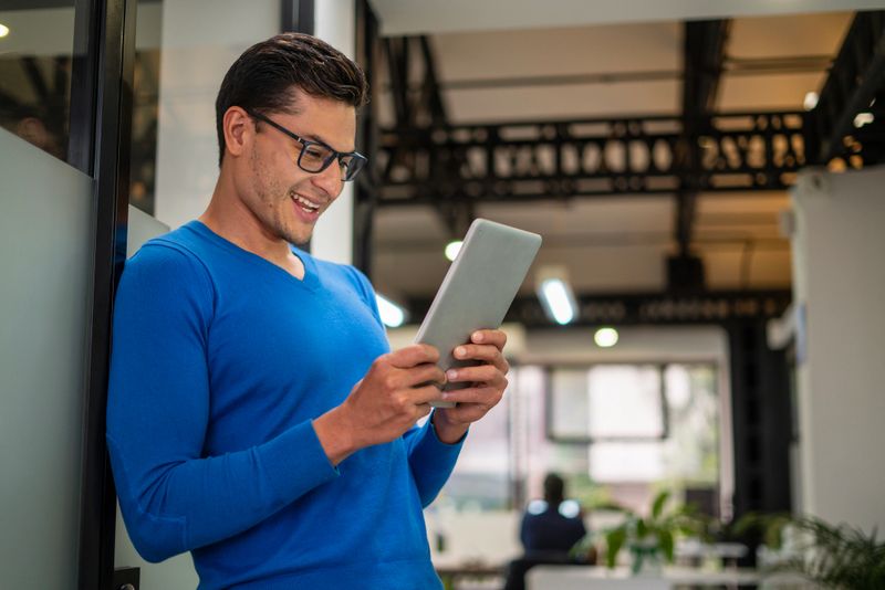 Man of latin ethnicity aged between 25-35 enjoying movies, sports and entertainment via streaming on his tablet