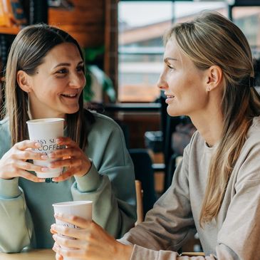 Two women happily chatting over coffee.