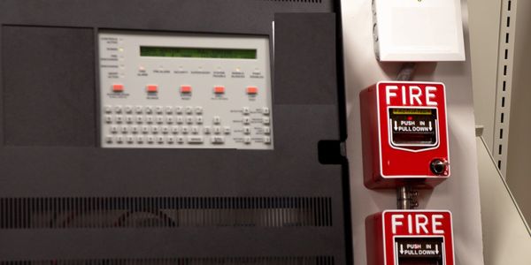Fire alarm pull stations and control panel mounted on wall.