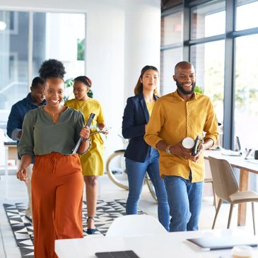 Happy diverse coworkers walking together in a bright modern office.