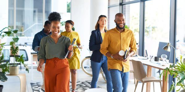 Happy diverse coworkers walking through a bright modern office.