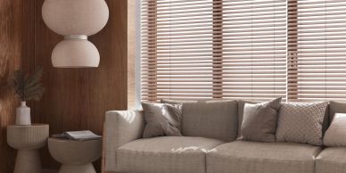 Cozy living room with beige sofa, wooden blinds, and soft natural lighting.