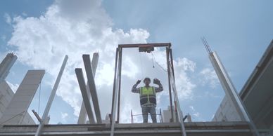 Construction worker guiding a glass panel installation on a building site.