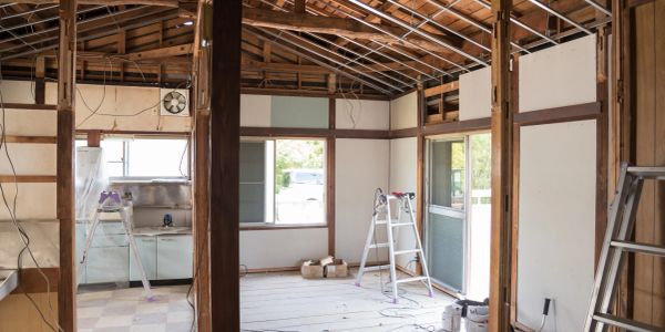 Interior of a house under renovation with exposed beams and ladders.