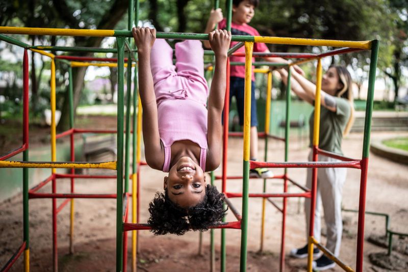 Portrait of a girl upside down in a jungle gym in a park