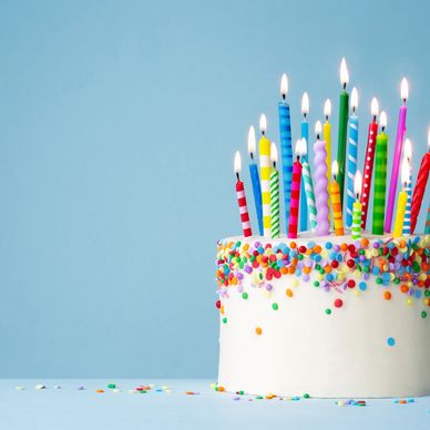 Birthday cake with lit candles and colorful sprinkles.