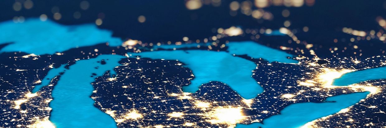 A glowing map of Michigan and the Great Lakes region at night, highlighting urban areas.