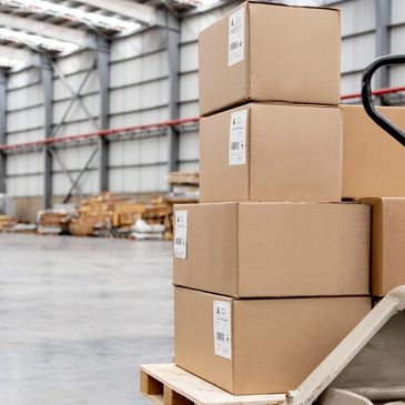 Stacked cardboard boxes on a pallet in a warehouse.