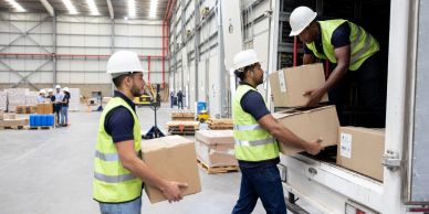 Workers loading boxes into a truck inside a warehouse.
