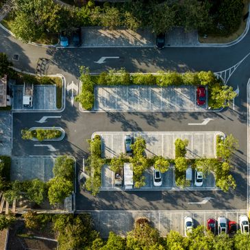 Empty parking lot with few cars and trees from above.
