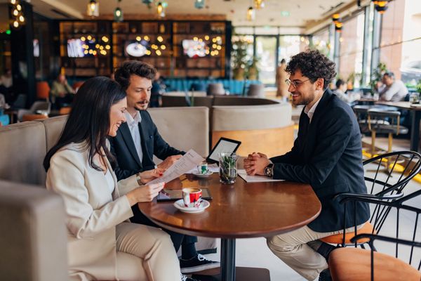 Three professionals having a meeting at a cafe, reviewing documents.