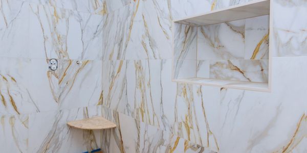 Marble tiled shower corner with built-in niche and corner shelf.
