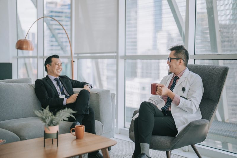 Asian Chinese male doctor discussion with hospital administrator senior management in hospital lounge