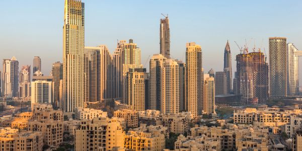 Sunlit city skyline with tall buildings and clear blue sky.