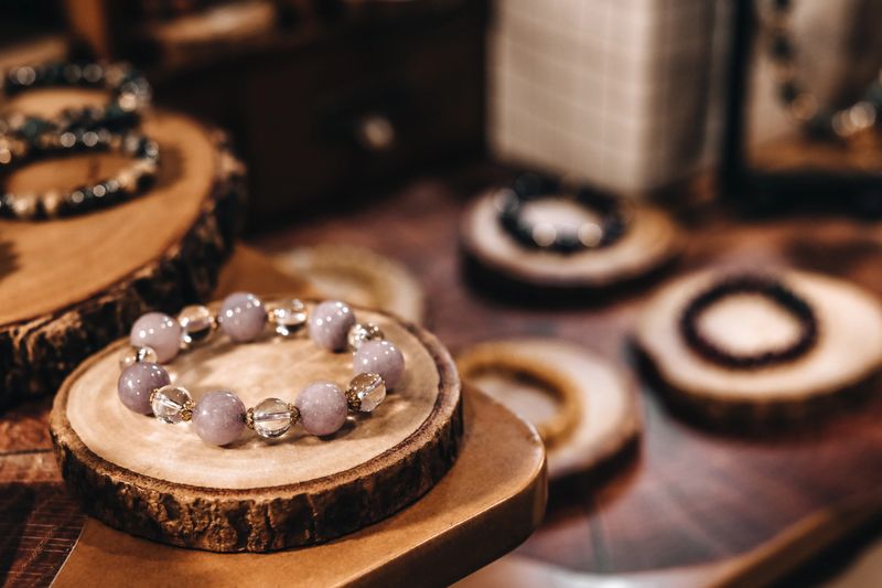 Bracelets of pink stone beads on a natural wood stand