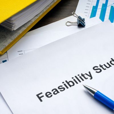 Documents titled 'Feasibility Study' with a pen and binder clips on a desk.