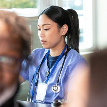 Focused nurse in blue scrubs working attentively indoors.