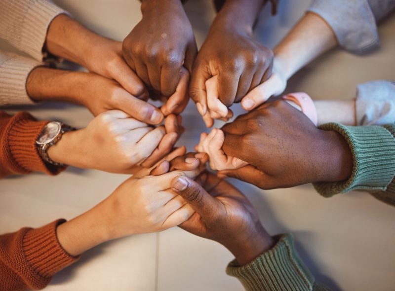 Holding hands, top view and group prayer of people with hope, support or faith, religion or spiritual praise. Community, teamwork and Christian friends, men and women praying together to worship God.