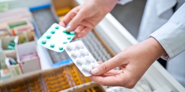 Hands holding blister packs of tablets in pharmacy.
