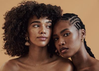 Two women embrace with natural beauty and confidence.