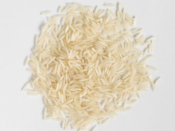 A pile of uncooked white rice grains on a white surface.