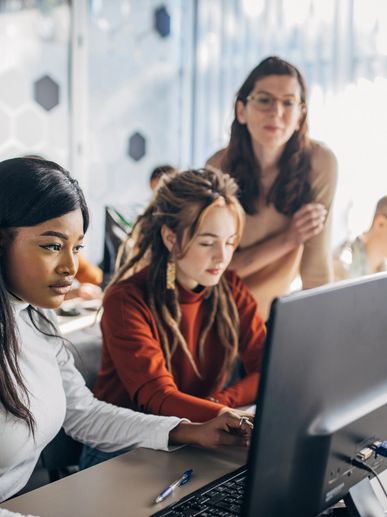 Three women collaborating at a computer in an office.