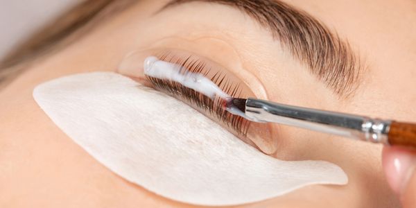 Applying eyelash treatment with a brush on closed eye.