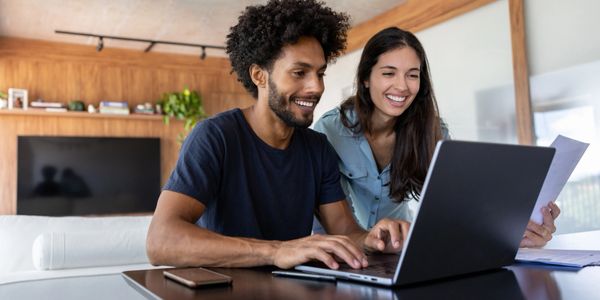 Happy couple using a laptop together at home.